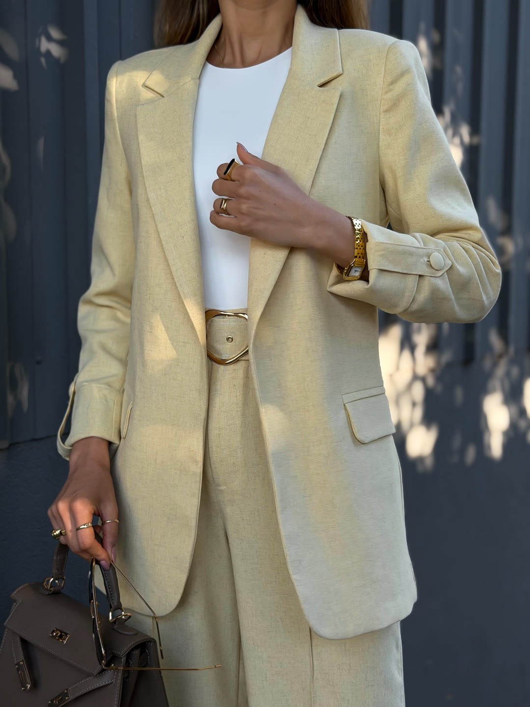 Detalhe do caimento do blazer amarelo-manteiga com cinto de fivela e bolsa taupe — alfaiataria ZAYA Boutique, Curitiba
