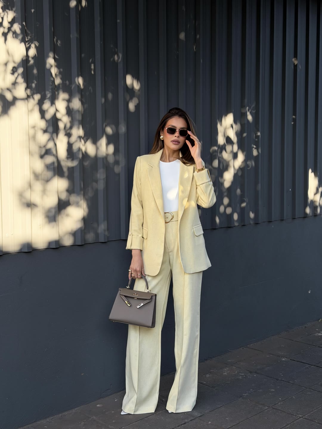 Regata branca com calça pantalona amarelo-manteiga e blazer no braço, vista de costas — ZAYA Boutique, Curitiba