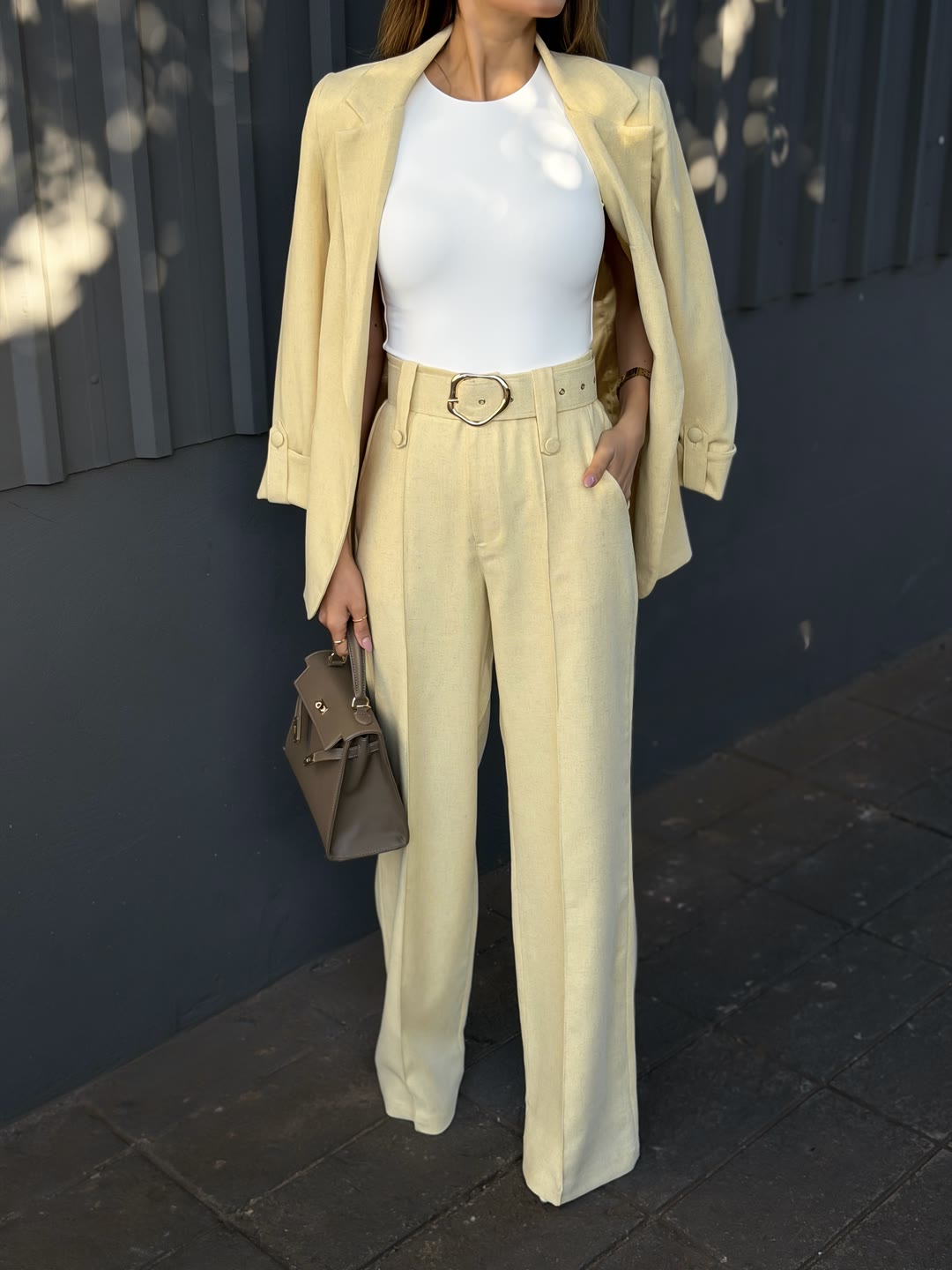 Conjunto amarelo-manteiga com blazer sobre os ombros, regata branca e pantalona com cinto — ZAYA Boutique, Batel